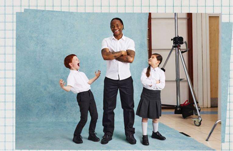Behind the scenes of a photoshoot with Raheem Sterling and two kids smiling.